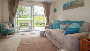 Een woonkamer met een bank, een salontafel en uitzicht door een glazen deur op een buitenruimte.