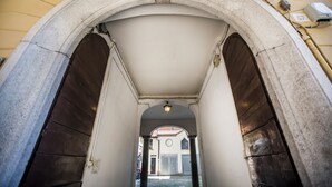 A corridor with a stone archway, a light fixture, and a building in the background. - Volta House by DM (Como)