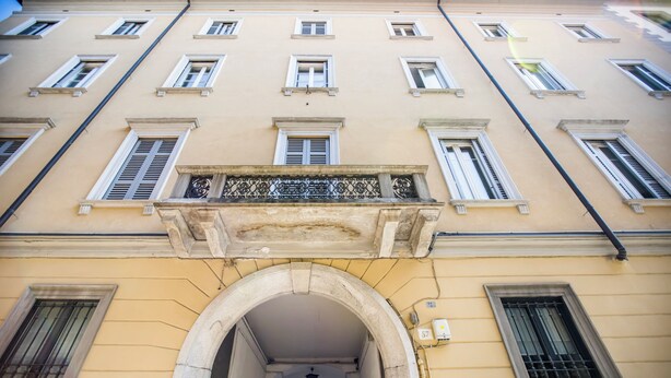 A building with multiple windows, a central archway, and a sign indicating a no parking zone. - Volta House by DM (Como)