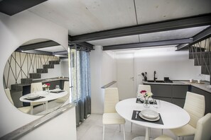 A modern kitchen with a dining area, a staircase, and a mirrored wall. - Volta House by DM (Como)