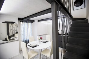 A modern dining area with a round table, white chairs, and a staircase with metal railings. - Volta House by DM (Como)