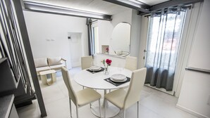 A modern dining area with a round table, white chairs, and a small side table. - Volta House by DM (Como)