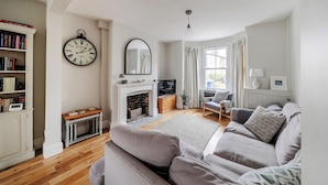 Ein Wohnzimmer mit Kamin, einer Couch, einem Bücherregal und einer Wanduhr.