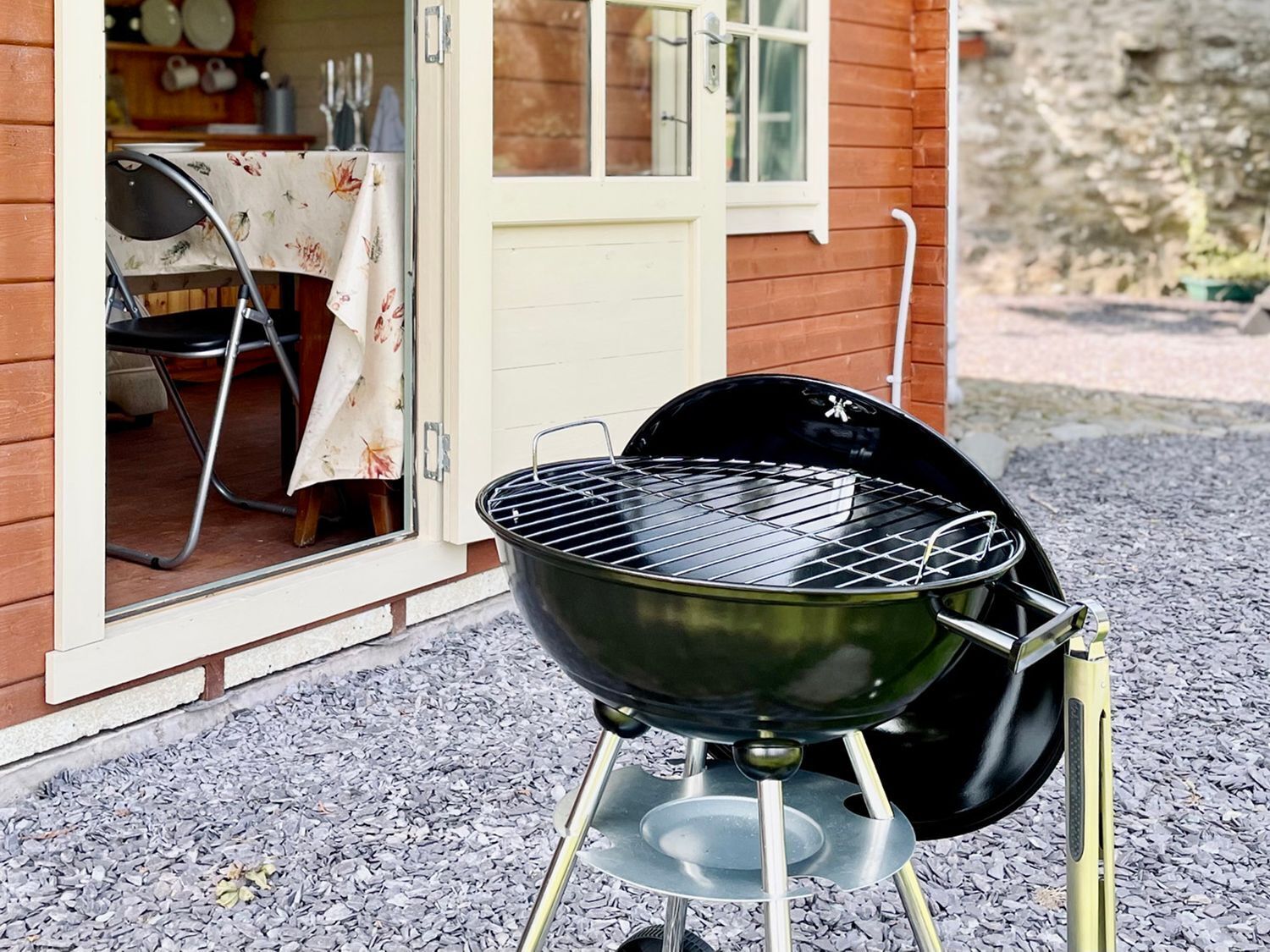 Una parrilla portátil frente a una casa, con una puerta y una ventana a la vista.