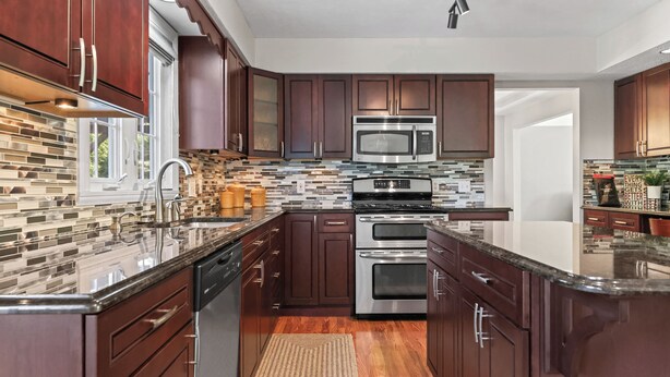 Una cocina moderna con armarios de madera oscura, electrodomésticos de acero inoxidable y un salpicadero con diseño.