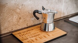 A stainless steel espresso machine on a wooden board with engraved text. - Casa Martini - Vatican City (Rome)