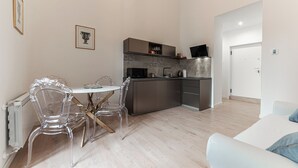 A modern kitchen with a microwave, kettle, and coffee machine. There is a dining area with a table and chairs. - Casa Martini - Vatican City (Rome)