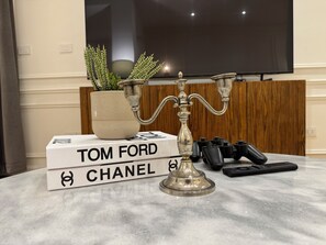 A marble table with a decorative candelabra, a potted plant, and a stack of books titled 'TOM FORD CHANEL'. - Baehler’s by The Dwelling Agency - Zamalek (Cairo Governorate)