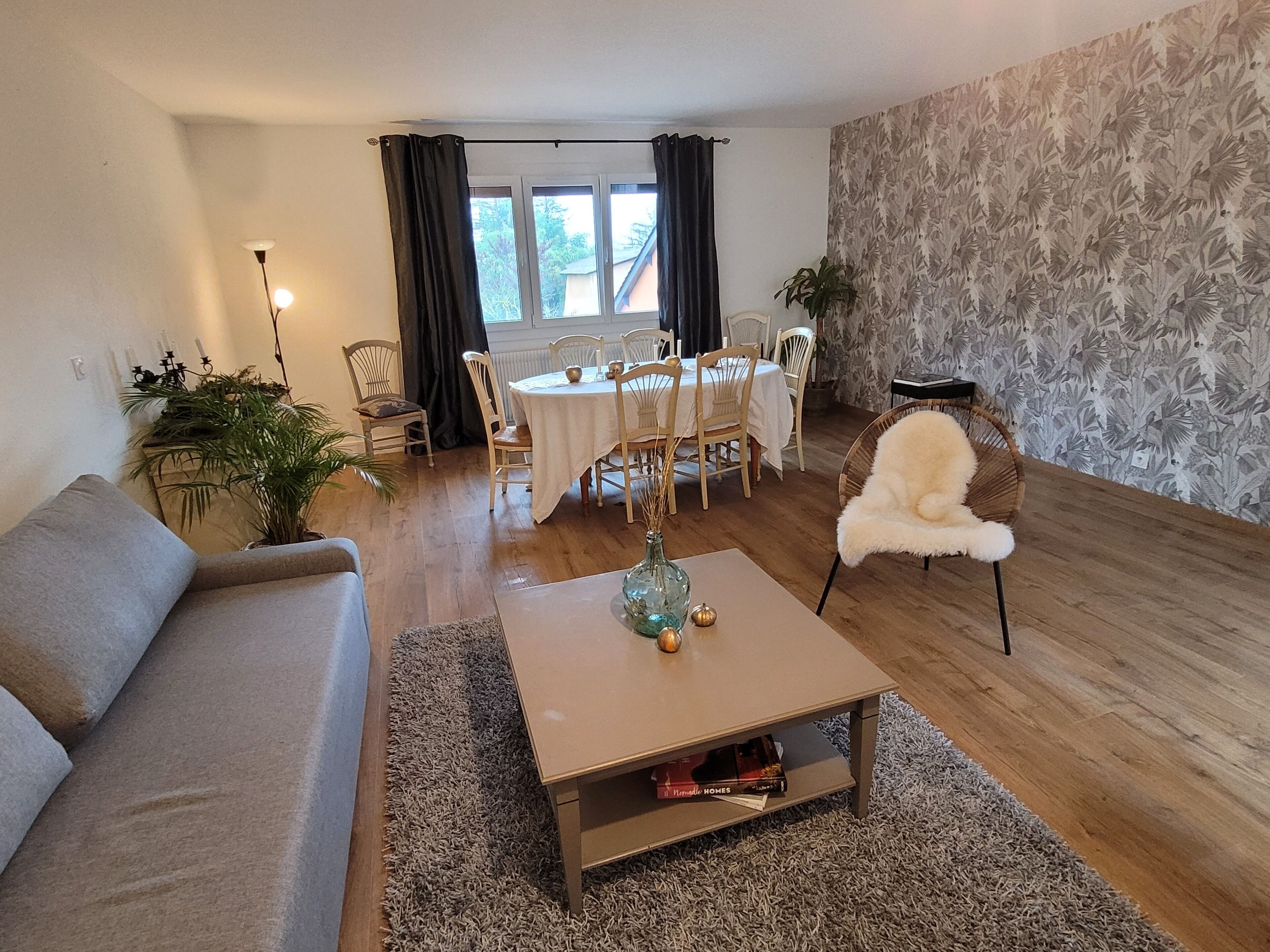 Un salon comprenant un canapé, une table basse, une table à manger, des chaises et une fenêtre avec des rideaux.