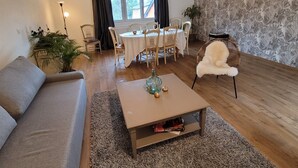 A living room with a sofa, coffee table, dining table, chairs, and a window with curtains. - Family home, a haven of peace at the foot of the Vercors mountains (Vif)