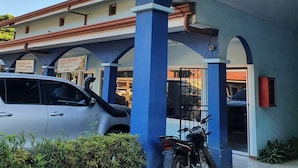 Un edificio con un cartello che riporta 'MarinaLoft' e una motocicletta parcheggiata sotto una struttura blu e bianca.