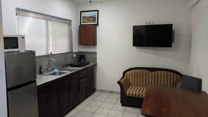 Una cucina compatta con forno a microonde, piano cottura, lavello e ventilatore a soffitto.