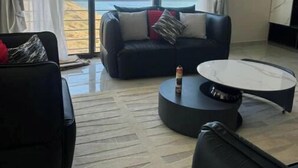 Un salon moderne avec un canapé, une table basse et une vue sur l’océan.