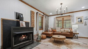 A living room with a fireplace, a sofa, a round coffee table, and a chandelier. - Sleeps 7*Great Location*Charming*Close to Attractions (GATLINBURG)