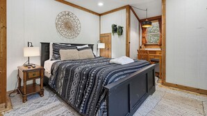 A bedroom with a bed, bedside tables, a wall-mounted decorative item, a window with curtains, and a wooden ceiling. - Sleeps 7*Great Location*Charming*Close to Attractions (GATLINBURG)