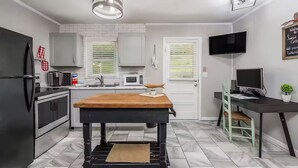 A compact kitchen with a central island, a microwave, a refrigerator, and a television. - New-Sunfish Cottage - Walk to Hidden Harbor Marina (Smithville)