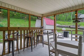 A covered outdoor seating area with wooden railings, metal chairs, and a table. - New-Sunfish Cottage - Walk to Hidden Harbor Marina (Smithville)