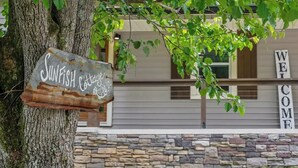 A rustic wooden sign with 'Sunfish Cottage' written on it, a stone wall, and a building with 'WELCOME' signs. - New-Sunfish Cottage - Walk to Hidden Harbor Marina (Smithville)