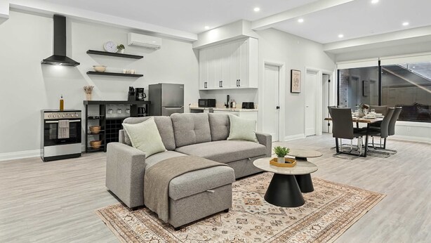 Ein modernes Wohnzimmer mit einem Ecksofa, einem runden Couchtisch und einem Essbereich mit Tisch und Stühlen.
