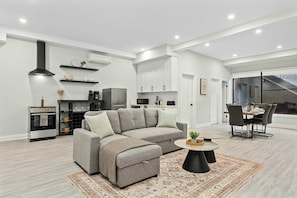 Una sala de estar moderna con un sofá modular, una mesa de centro y un comedor con mesa y sillas.