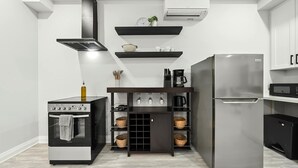 Eine moderne Küche mit Einbauofen, Edelstahl-Kühlschrank und einer schwarzen Kücheninsel mit Regalen.