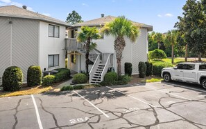 A two-story building with a parking lot, a staircase, and a white SUV parked in the lot. - 🌊Great Location | Walk to Beach | 2 Pools | Crystal Village II 26A⛱️ (Miramar Beach)