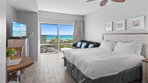 A hotel room with a bed, a desk with a computer, a dining table, and a view of the ocean. - 🌸Gulf Views | Resort Amenities | Walk to the Beach | Luau II 6631/6633🌸 (Miramar Beach)