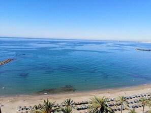 Ein Strand mit klarem, blauem Wasser, sandigem Ufer und Palmen.