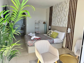 A hotel room with a bed, a chair, a small table, a plant, and a wardrobe. - Diana 507 - BeachFront Studio with Sun All Day (Marbella)
