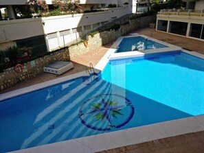 A swimming pool with a circular design on the water, surrounded by stone walls and a tiled deck. - 0. Diana 101 (Marbella)