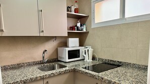 Een keuken met granieten aanrecht, een magnetron, een waterkoker en een vaatwasser.