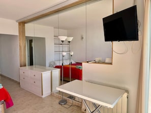 A hotel room with a bed, a desk, a dresser, a TV, and a large mirror. - 0. Diana 101 (Marbella)
