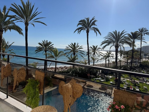 A pool area with a view of the ocean, palm trees, and a beach. - 0. Skol Marbella 111A (Marbella)