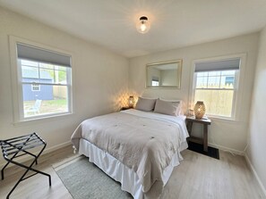Een slaapkamer met een bed, nachtlampjes, een spiegel en een raam.