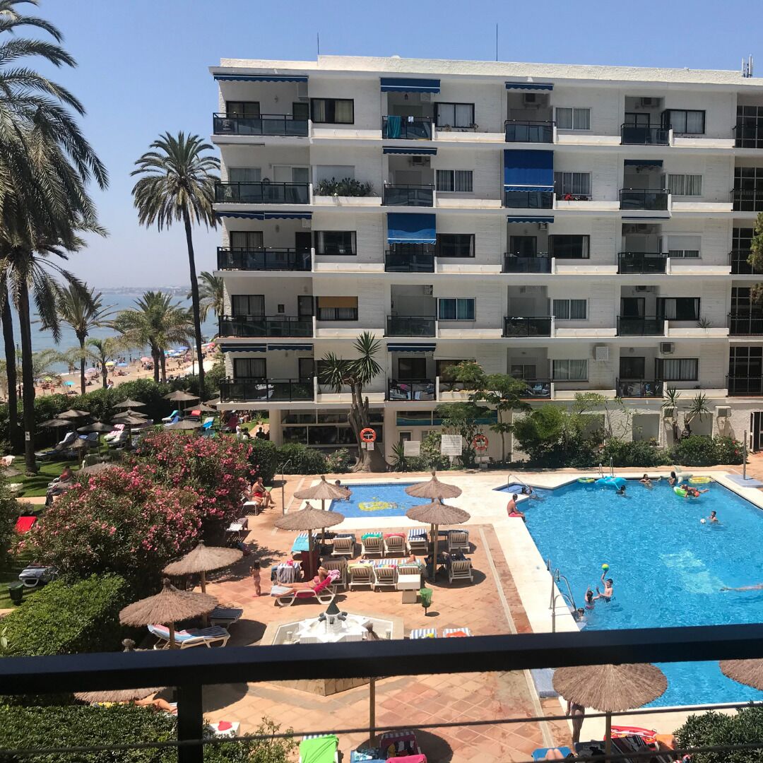 Et hotel med flere etager, altaner, swimmingpool og havudsigt.