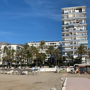 Ein mehrstöckiges Hotel mit Balkonen, Palmen und blauem Himmel.