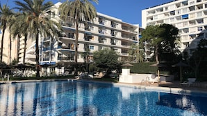 A hotel with a swimming pool, palm trees, and a multi-story building with balconies. - Skol Marbella 118C Beachfront Central with pool & wifi (Marbella)