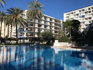A hotel with a swimming pool, palm trees, and a multi-story building with balconies. - Skol Marbella 118C Beachfront Central with pool & wifi (Marbella)