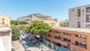 Un edificio de varios pisos con un estacionamiento y una montaña al fondo.