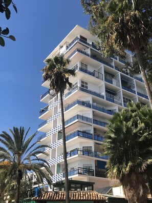 A multi-story hotel with balconies, palm trees, and a clear blue sky. - 1. Skol Marbella 328C (Marbella)