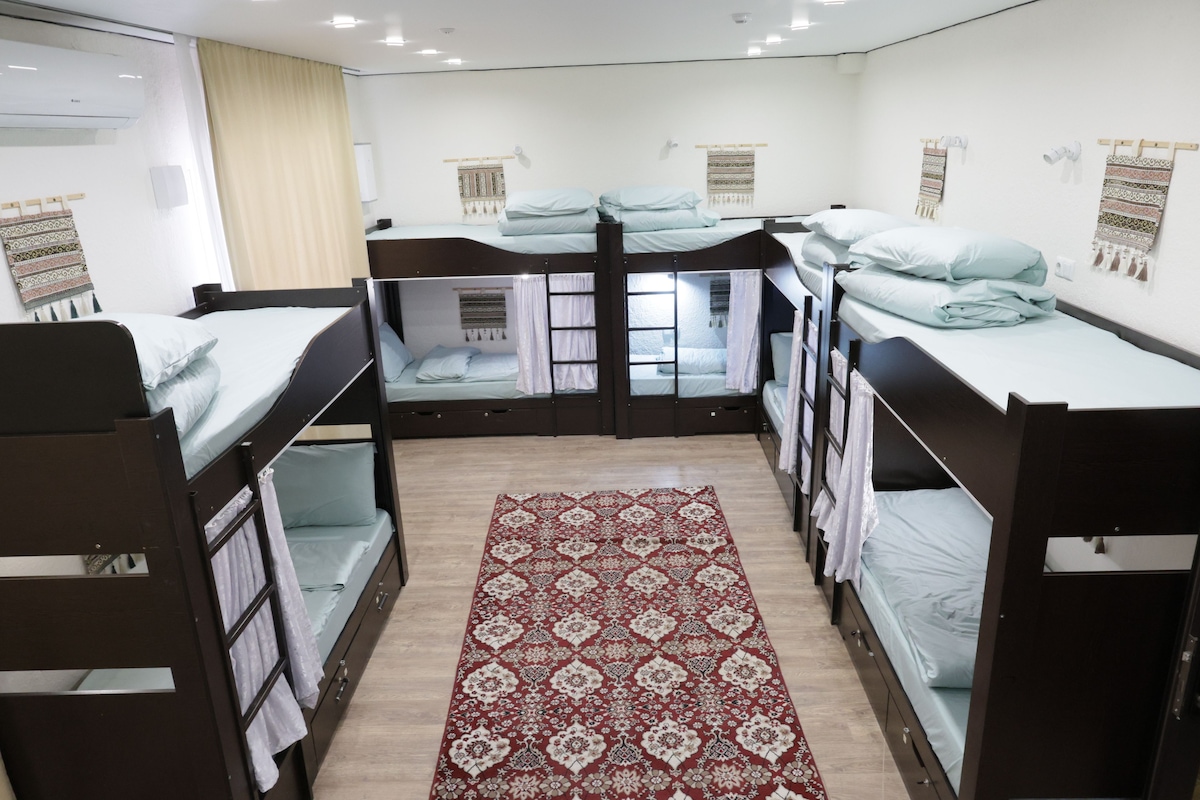 A room with bunk beds, a patterned rug, and wall decorations.