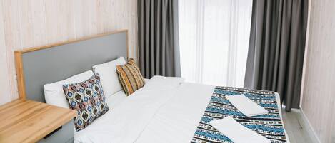 A hotel room with a bed, a nightstand, and a window with curtains.
