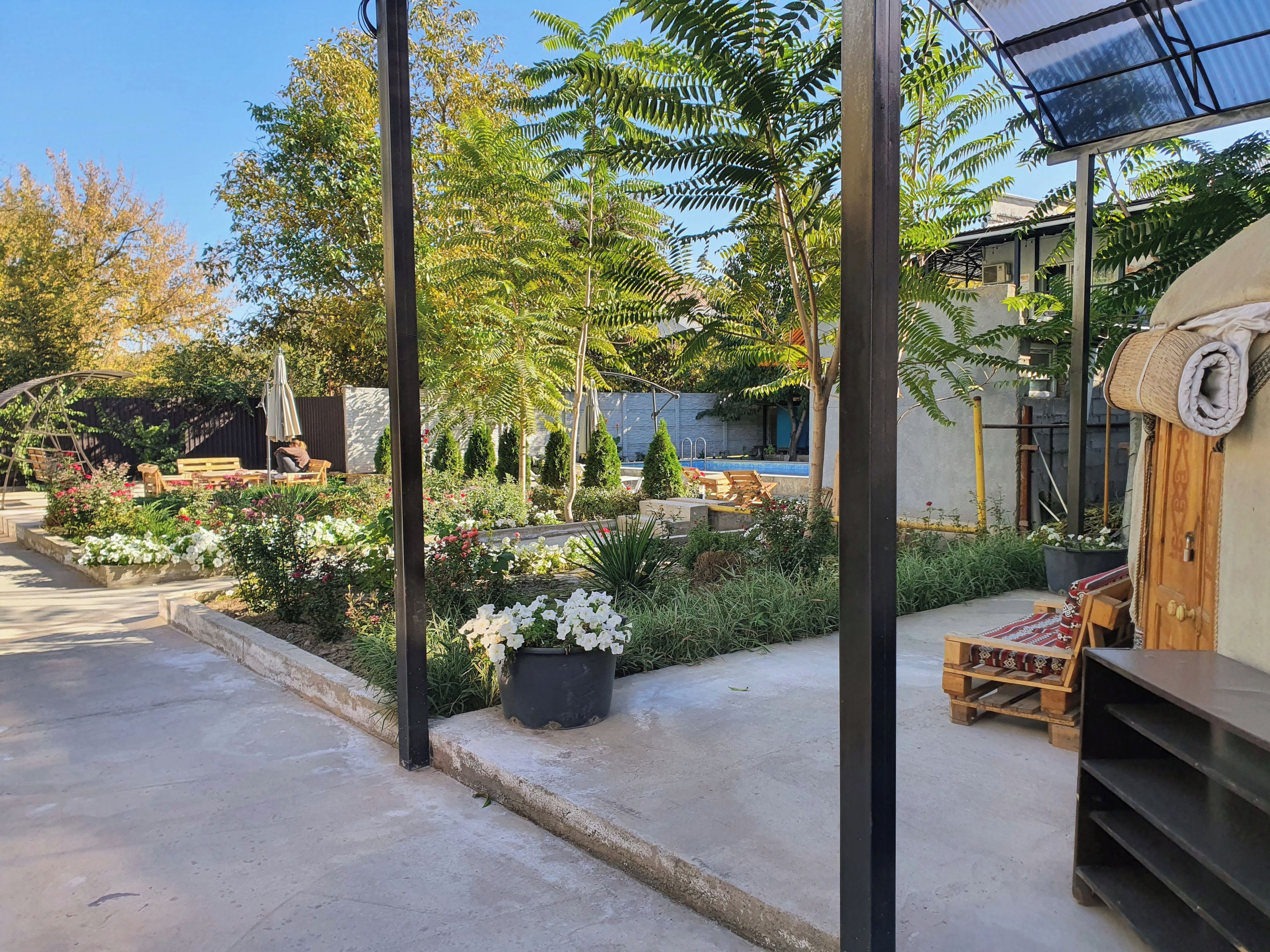 A garden with a pool, outdoor furniture, and a pergola.