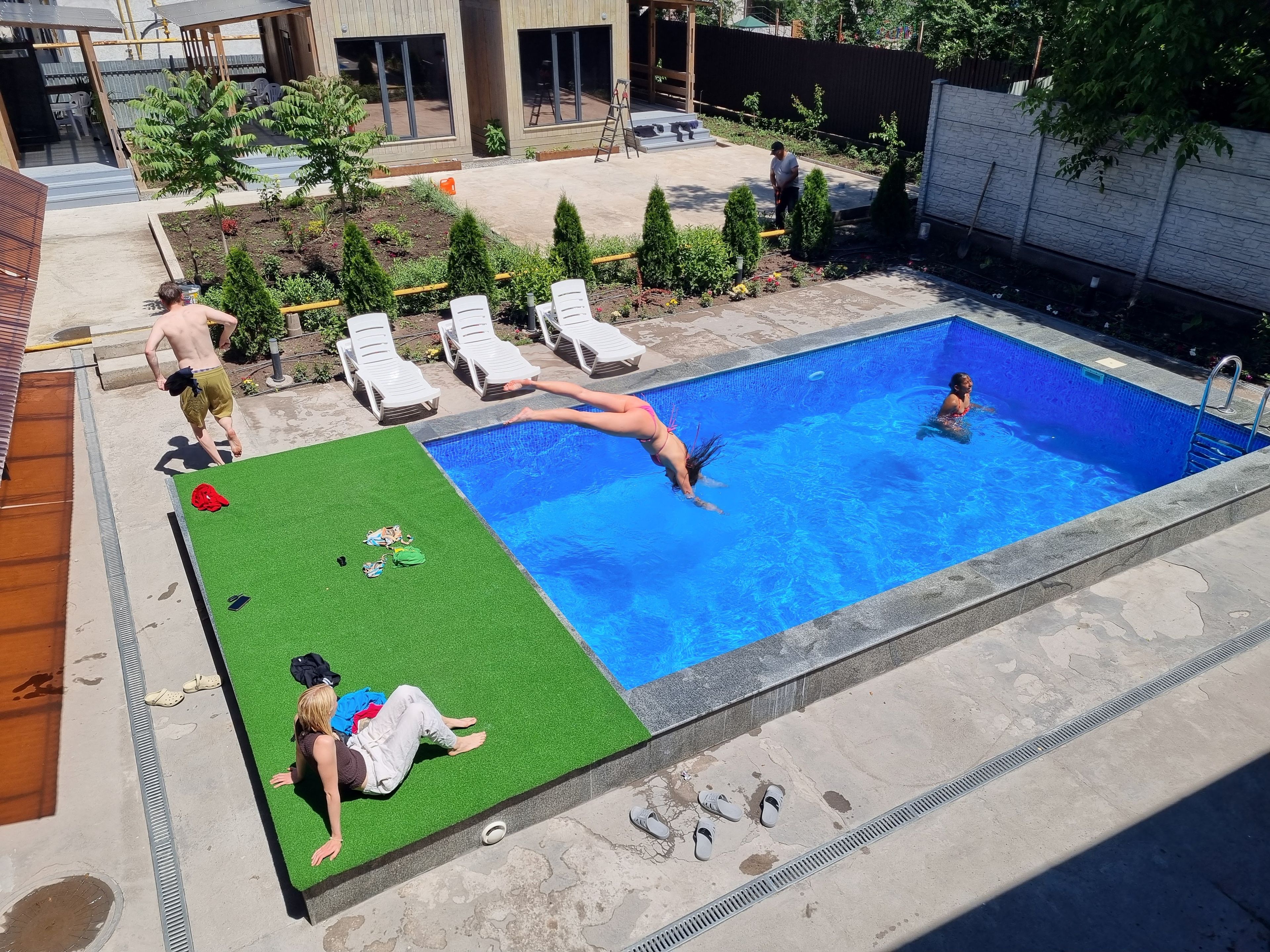 A swimming pool with a grassy area and lounge chairs.