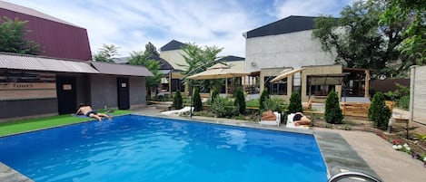 Une piscine avec des chaises longues et un espace salon abrité.