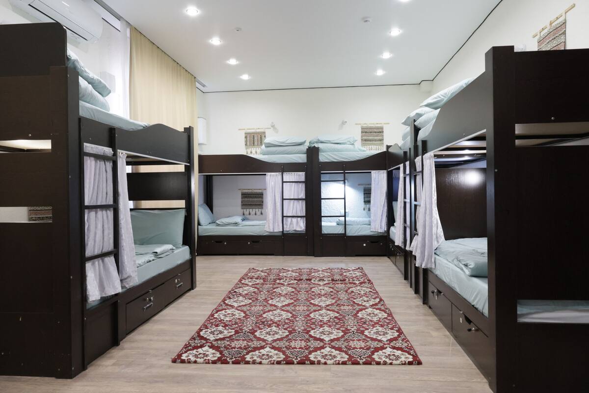 Una habitación con literas, un tapete estampado y una ventana con cortinas.