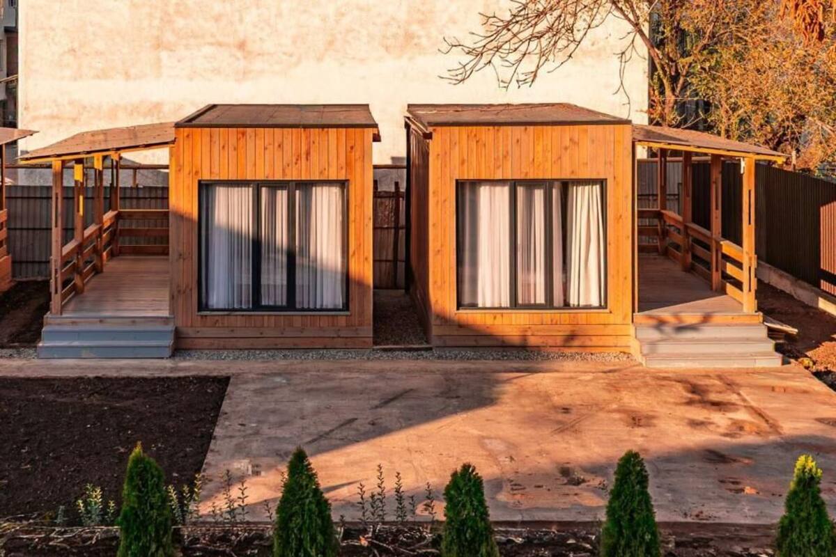 Dos cabañas de madera con ventanas, una terraza de madera y un camino de hormigón.