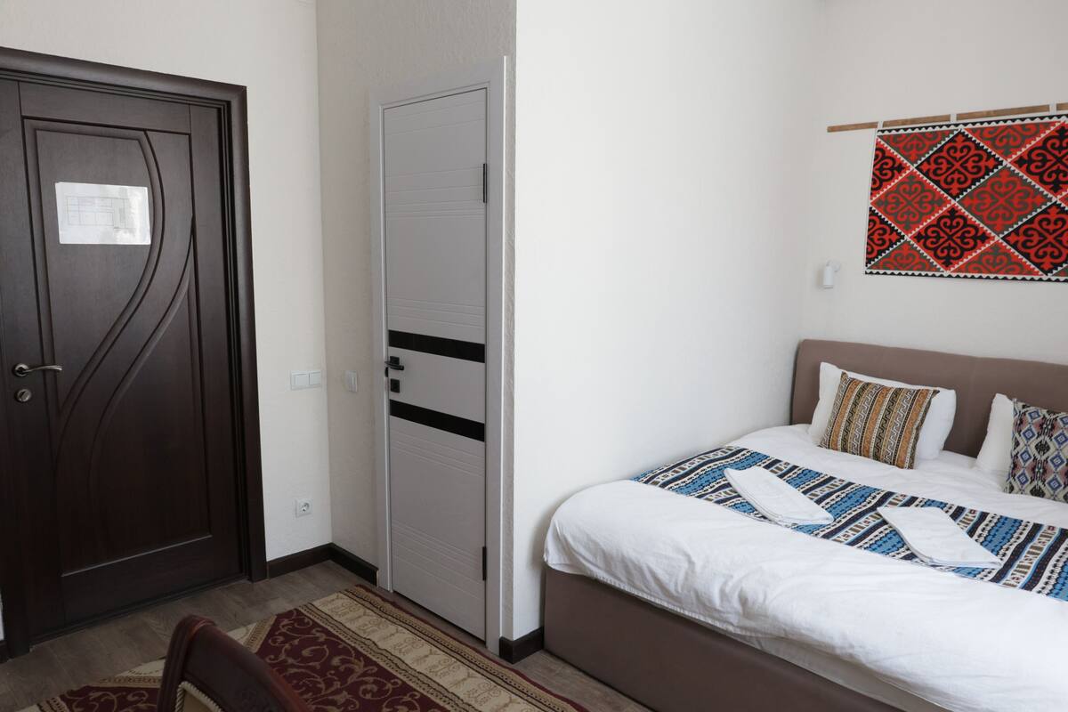 Un dormitorio con cama, armario, puerta y un tapiz de pared con estampado.