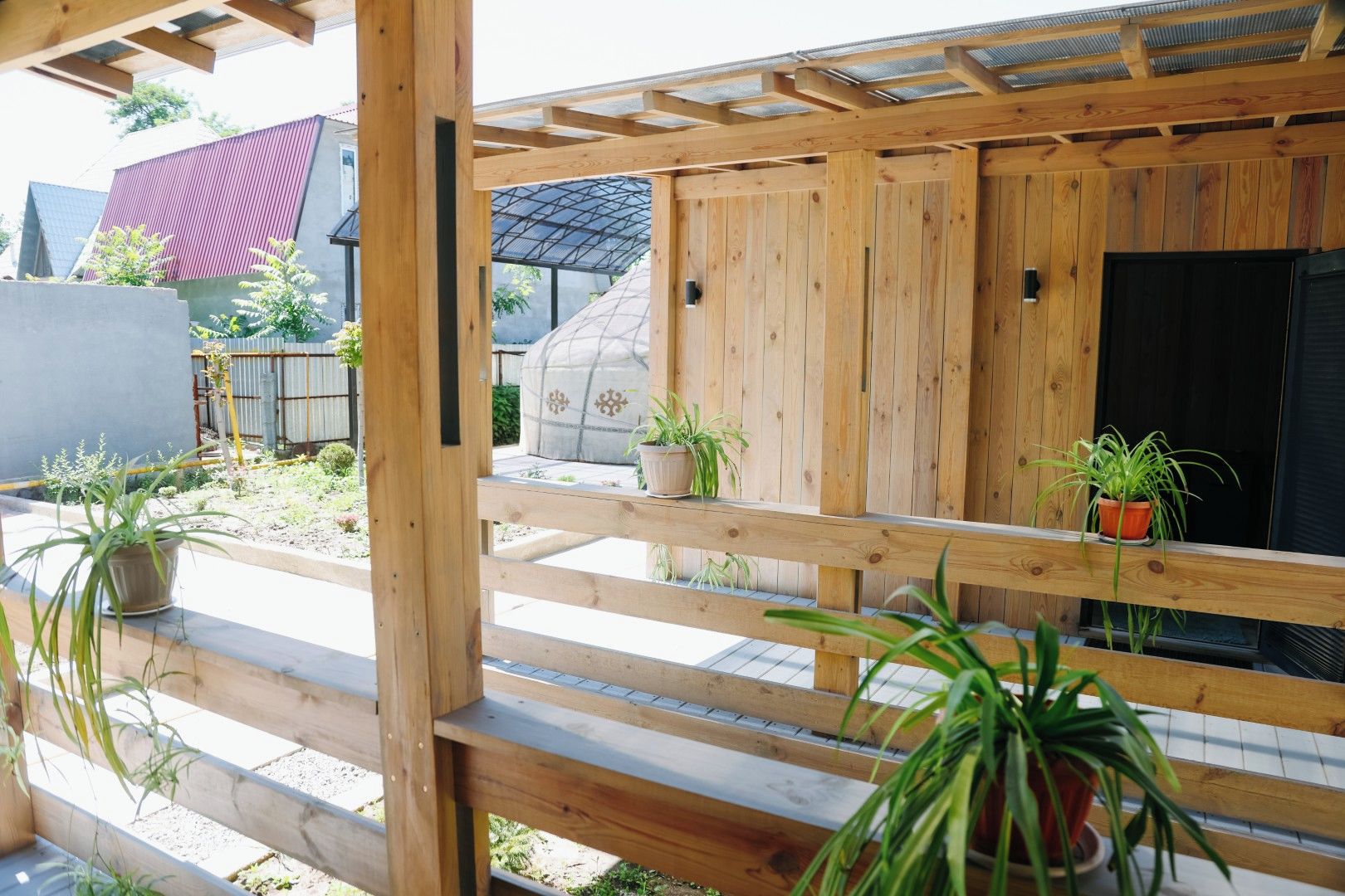 Una estructura de pérgola de madera con plantas en macetas al nivel del suelo.