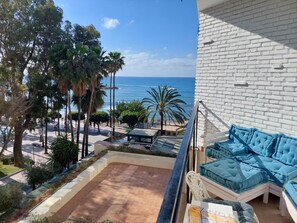 Un balcón con vistas al mar, una pared de ladrillo blanco y muebles azules.